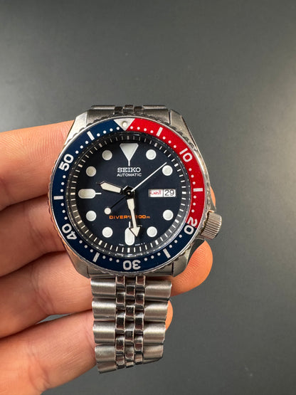 Seiko SKX009K2 Pepsi – arabische Wochentagsanzeige, Freitag in Rot